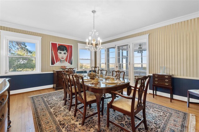 dining area with hardwood / wood-style floors, a notable chandelier, a healthy amount of sunlight, and ornamental molding