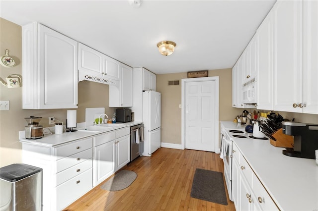 kitchen with white cabinetry, sink, light hardwood / wood-style floors, and white appliances