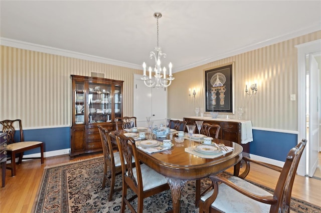 dining area with a notable chandelier, ornamental molding, and light hardwood / wood-style flooring