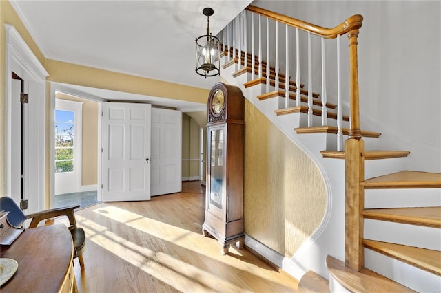 entryway with light hardwood / wood-style floors, crown molding, and a chandelier