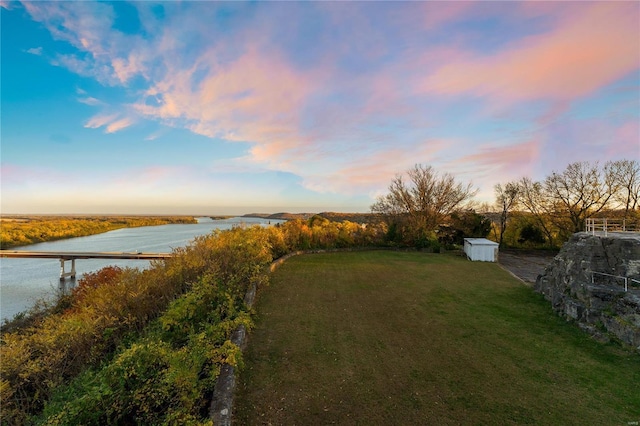 yard at dusk with a water view and a storage unit