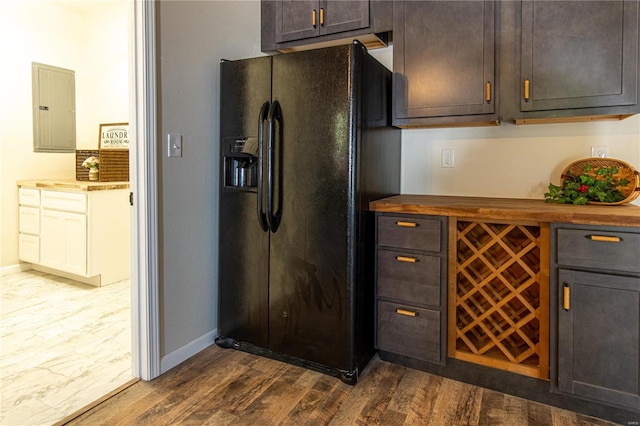 kitchen featuring electric panel, black fridge, butcher block countertops, dark brown cabinets, and dark hardwood / wood-style flooring