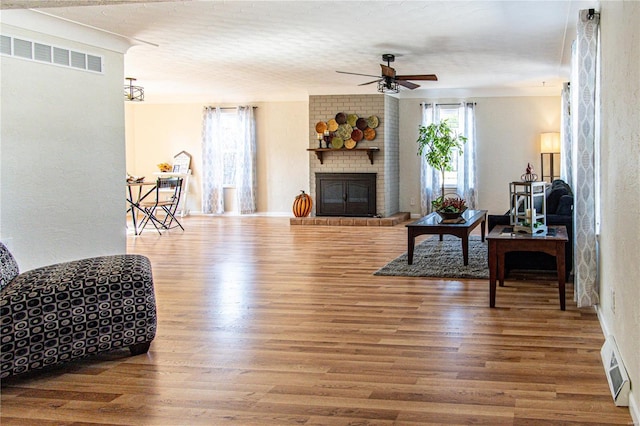 living room with hardwood / wood-style flooring, ceiling fan, and a fireplace