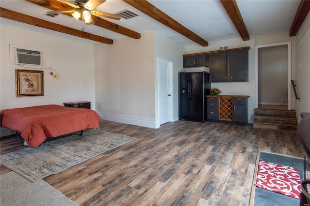 bedroom featuring dark wood-type flooring, black refrigerator with ice dispenser, ceiling fan, beam ceiling, and a wall unit AC