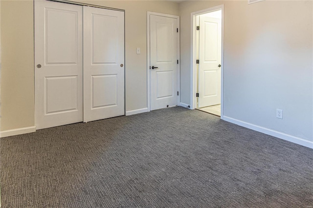 unfurnished bedroom featuring dark carpet and a closet