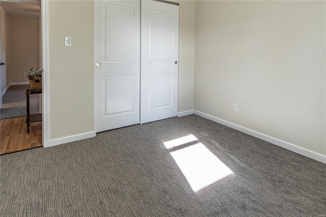 unfurnished bedroom featuring dark carpet and a closet