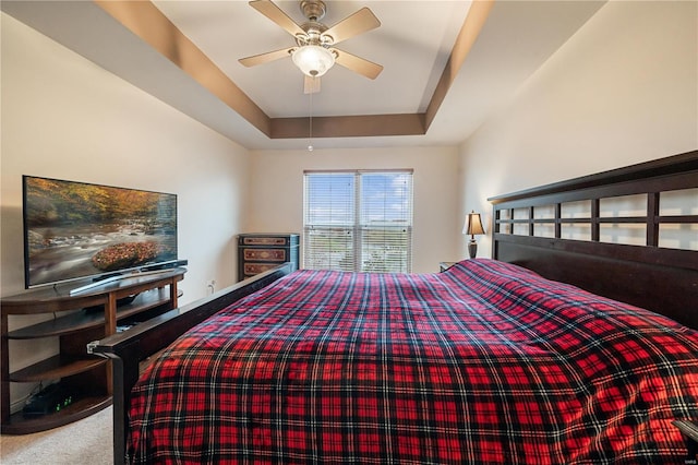 carpeted bedroom featuring a tray ceiling and ceiling fan