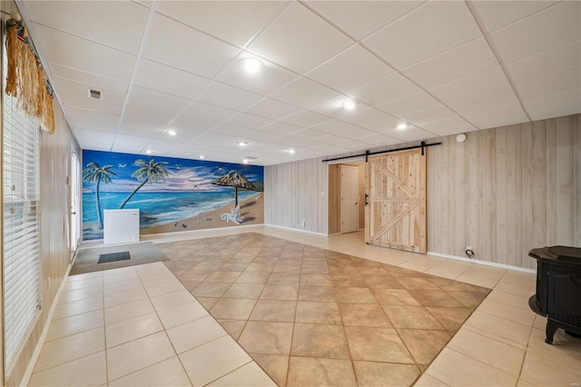 interior space with a barn door, tile patterned floors, and wood walls