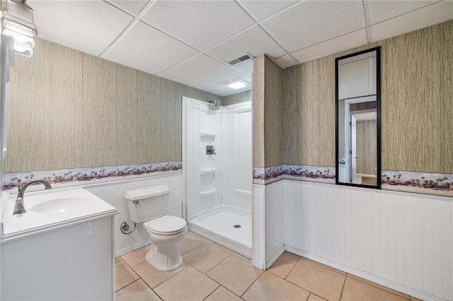 bathroom with tile patterned floors, a paneled ceiling, a shower, and vanity