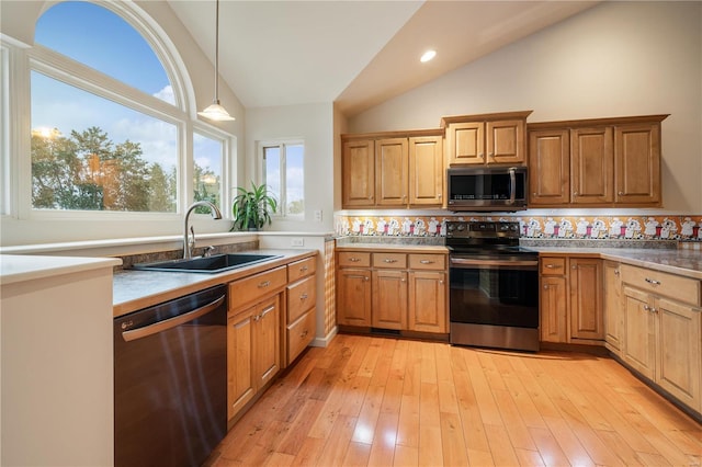 kitchen with decorative backsplash, stainless steel appliances, sink, pendant lighting, and light hardwood / wood-style flooring