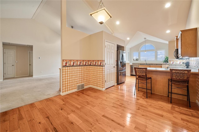 kitchen featuring light carpet, a kitchen breakfast bar, sink, appliances with stainless steel finishes, and kitchen peninsula