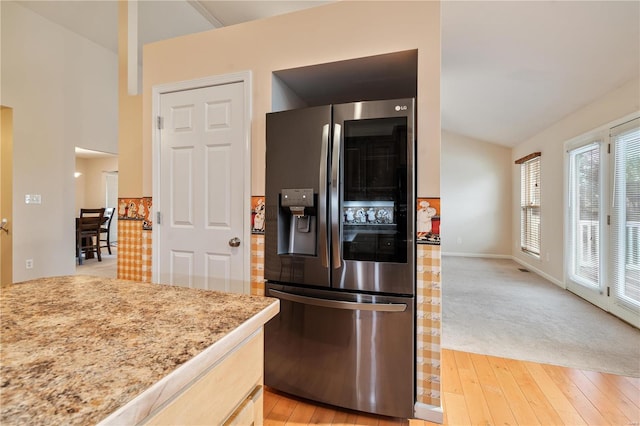 kitchen with lofted ceiling, light brown cabinetry, stainless steel refrigerator with ice dispenser, and light carpet