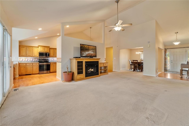 unfurnished living room with ceiling fan, light wood-type flooring, and high vaulted ceiling