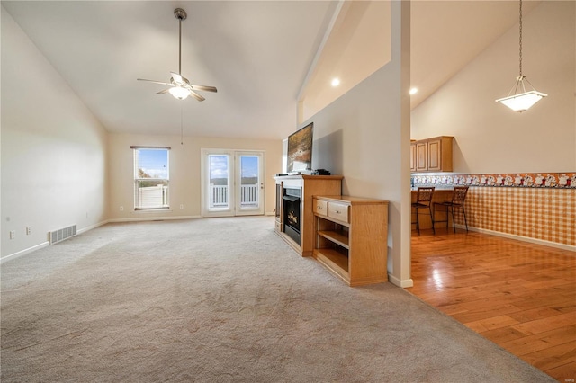 living room featuring ceiling fan, light wood-type flooring, and high vaulted ceiling