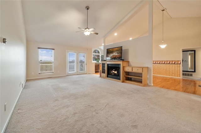 unfurnished living room with carpet, ceiling fan, and high vaulted ceiling