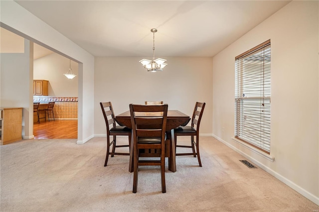 dining space with carpet floors and a chandelier