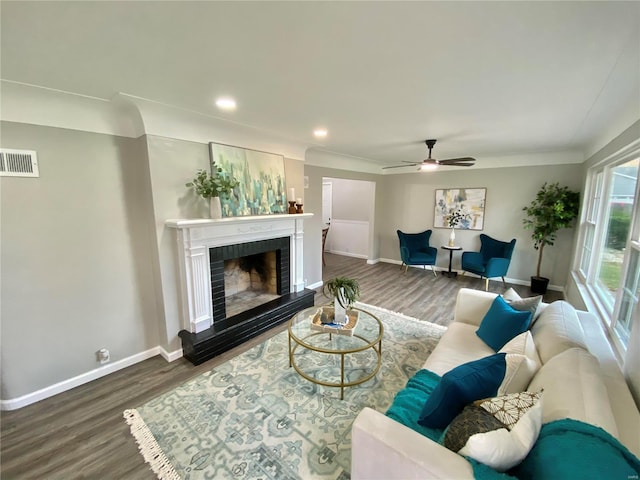 living room featuring hardwood / wood-style floors, ceiling fan, and a brick fireplace