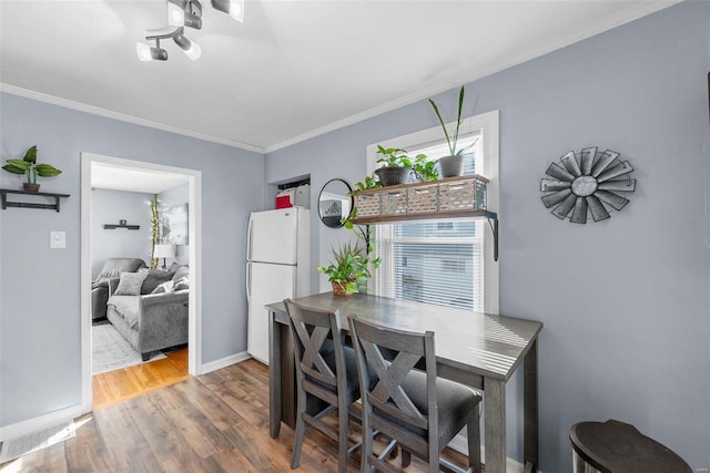 dining space with ornamental molding and hardwood / wood-style flooring