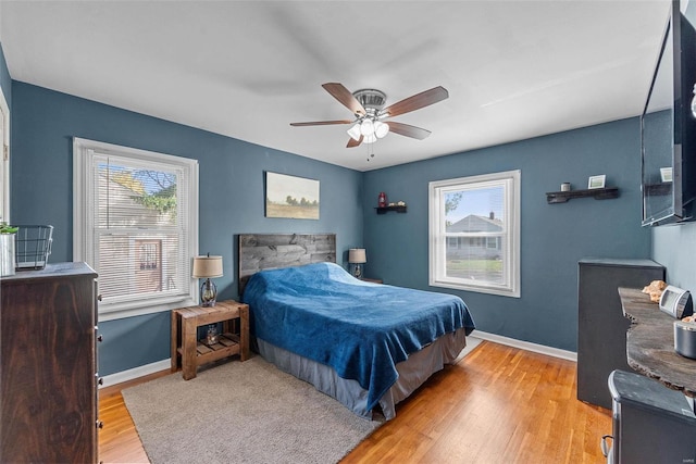 bedroom featuring light hardwood / wood-style floors, ceiling fan, and multiple windows