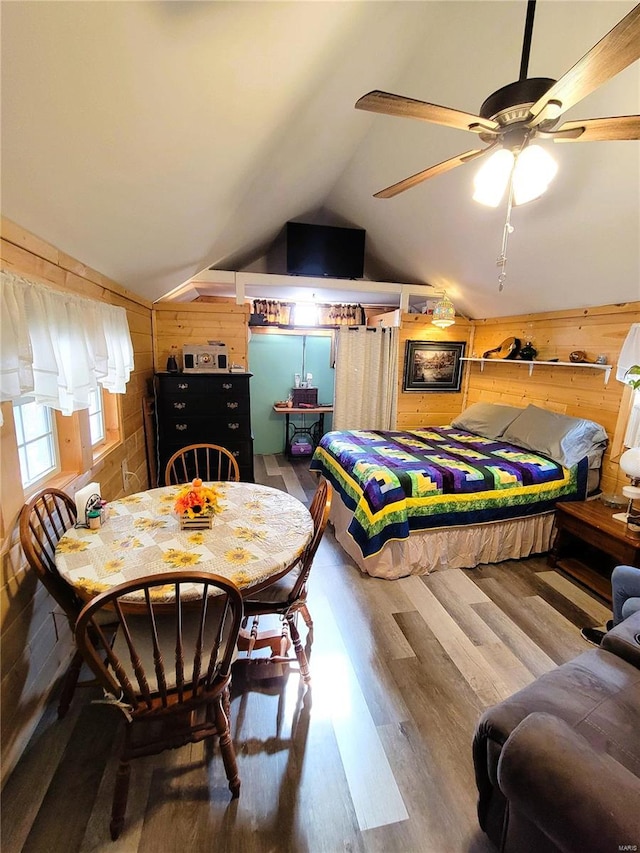 bedroom with hardwood / wood-style floors, wood walls, ceiling fan, and vaulted ceiling