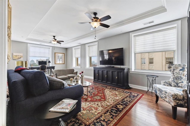 living room featuring hardwood / wood-style floors, ceiling fan, a raised ceiling, and ornamental molding