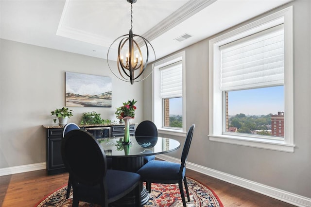 dining area with dark hardwood / wood-style floors, a raised ceiling, crown molding, and a chandelier