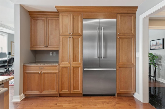 kitchen featuring light stone countertops, light hardwood / wood-style flooring, and built in fridge