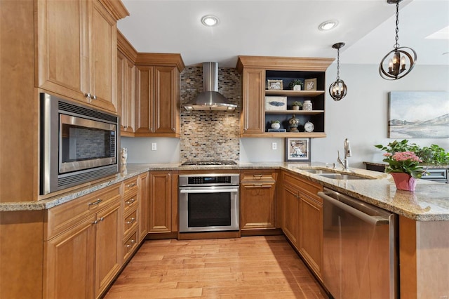 kitchen with pendant lighting, wall chimney range hood, kitchen peninsula, and appliances with stainless steel finishes