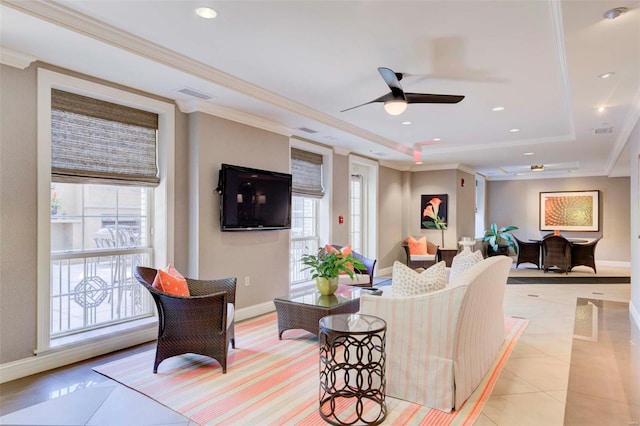 living room with light tile patterned floors, a tray ceiling, ceiling fan, and ornamental molding