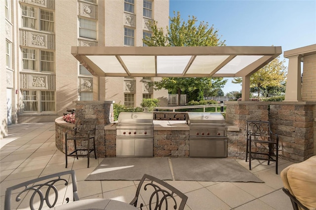 view of patio with area for grilling, an outdoor bar, and an outdoor kitchen