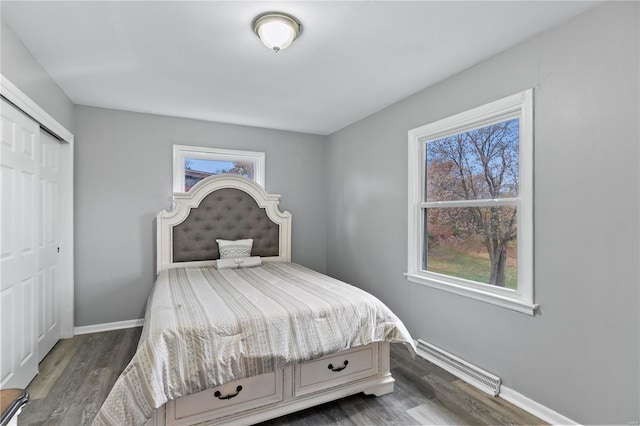 bedroom featuring a baseboard heating unit, a closet, and dark wood-type flooring