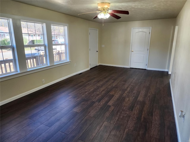 empty room with ceiling fan, dark hardwood / wood-style floors, and a textured ceiling