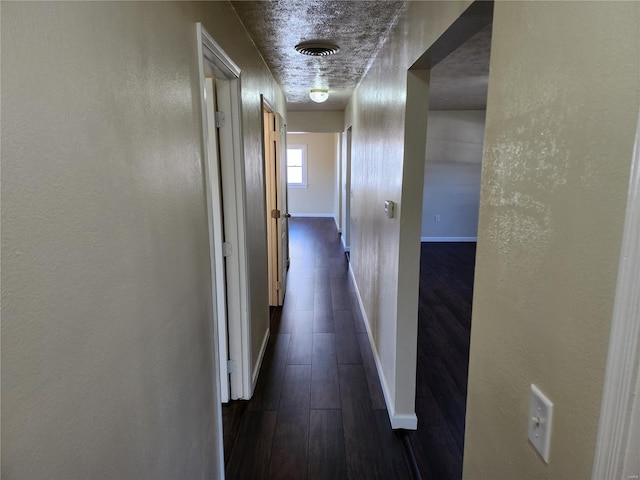 hall featuring dark wood-type flooring and a textured ceiling