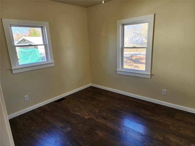 spare room with dark hardwood / wood-style floors and plenty of natural light