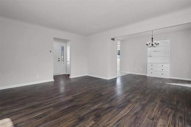 empty room with dark hardwood / wood-style flooring and an inviting chandelier