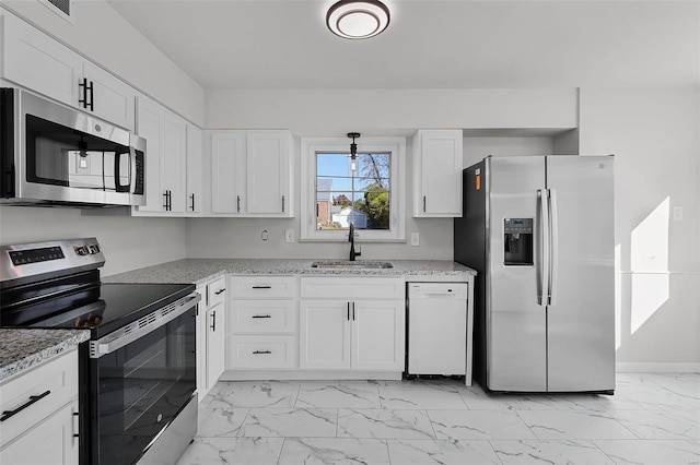 kitchen with white cabinets, appliances with stainless steel finishes, light stone countertops, and sink