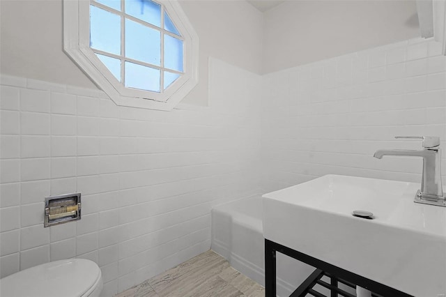 bathroom with sink, tile walls, and toilet