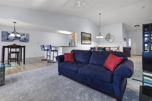 living room featuring light hardwood / wood-style flooring, ceiling fan with notable chandelier, and vaulted ceiling