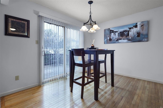 dining room with hardwood / wood-style floors, a textured ceiling, and a chandelier