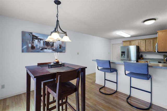 dining area featuring light wood-type flooring and a textured ceiling