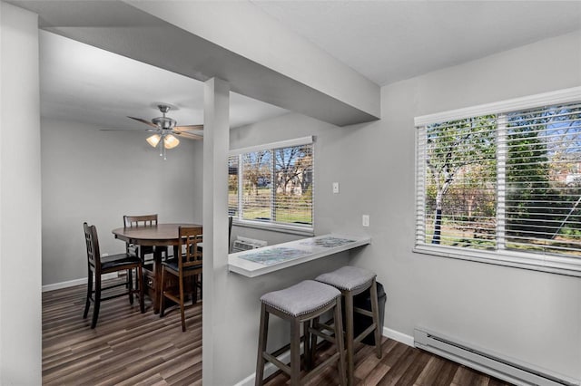 dining space with a wealth of natural light, ceiling fan, dark hardwood / wood-style floors, and a baseboard heating unit