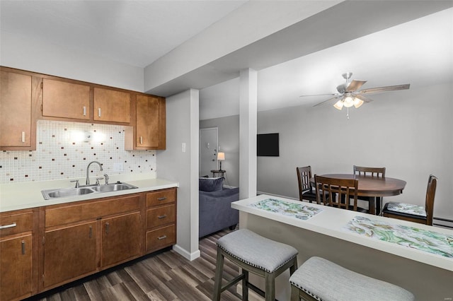 kitchen featuring dark hardwood / wood-style flooring, tasteful backsplash, ceiling fan, and sink