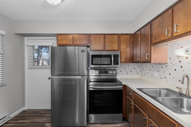 kitchen featuring sink, stainless steel appliances, tasteful backsplash, dark hardwood / wood-style floors, and a baseboard heating unit