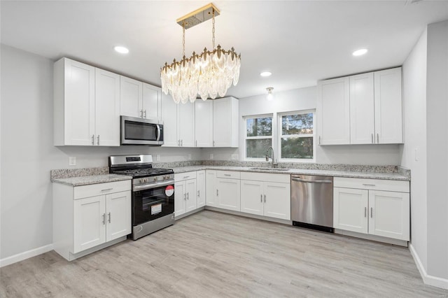 kitchen featuring white cabinets, appliances with stainless steel finishes, light wood-type flooring, a sink, and recessed lighting