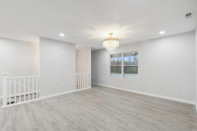 unfurnished room with baseboards, visible vents, wood finished floors, an inviting chandelier, and recessed lighting