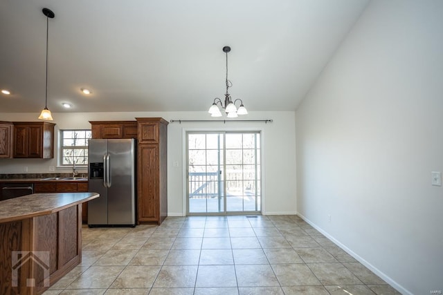 kitchen featuring decorative light fixtures, lofted ceiling, stainless steel appliances, and an inviting chandelier