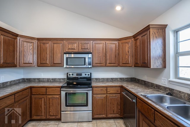 kitchen with light tile patterned floors, a healthy amount of sunlight, lofted ceiling, and appliances with stainless steel finishes