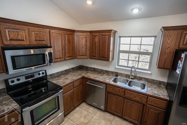 kitchen featuring light tile patterned floors, stainless steel appliances, vaulted ceiling, and sink