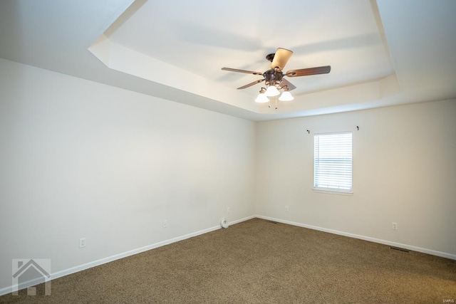 spare room featuring a tray ceiling, ceiling fan, and carpet floors