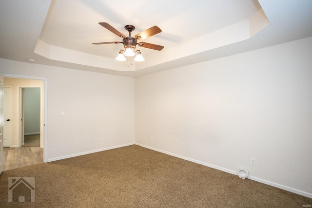 carpeted spare room featuring a raised ceiling and ceiling fan